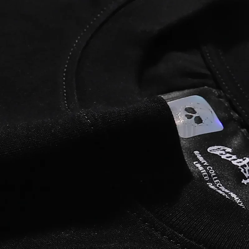 Detailed close-up of the tee's neck label, featuring wash care instructions and subtle brand branding in a clean, minimalist typography