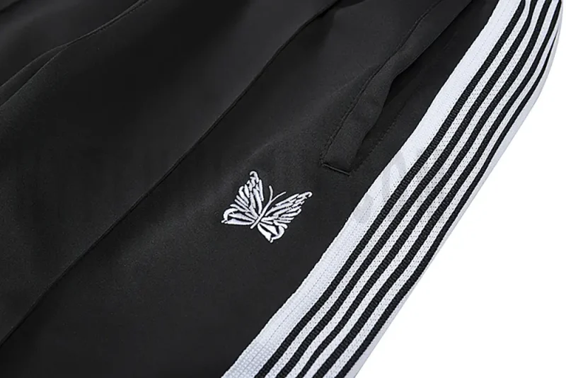 Detailed view of the pocket and intricate butterfly embroidery on the track pants.