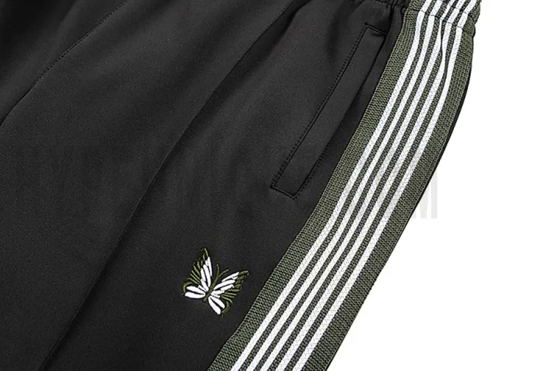 Detailed view of the pocket and intricate butterfly embroidery on the track pants.