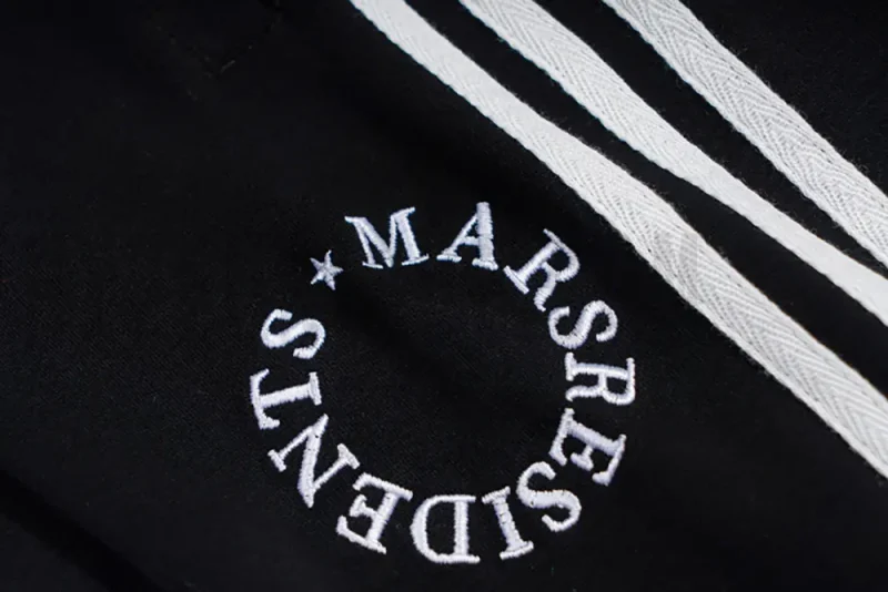 White signature embroidered logo on the black pants.