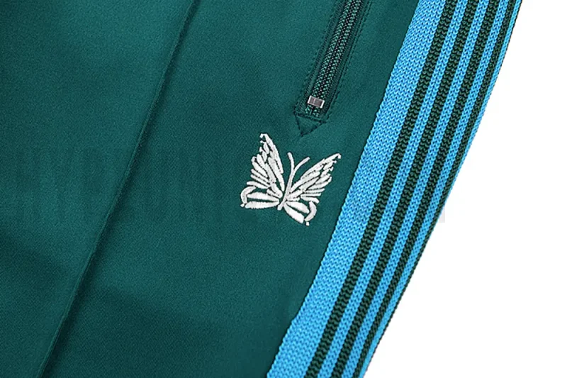 Close-up detail of the track pants pocket and delicate butterfly embroidery.