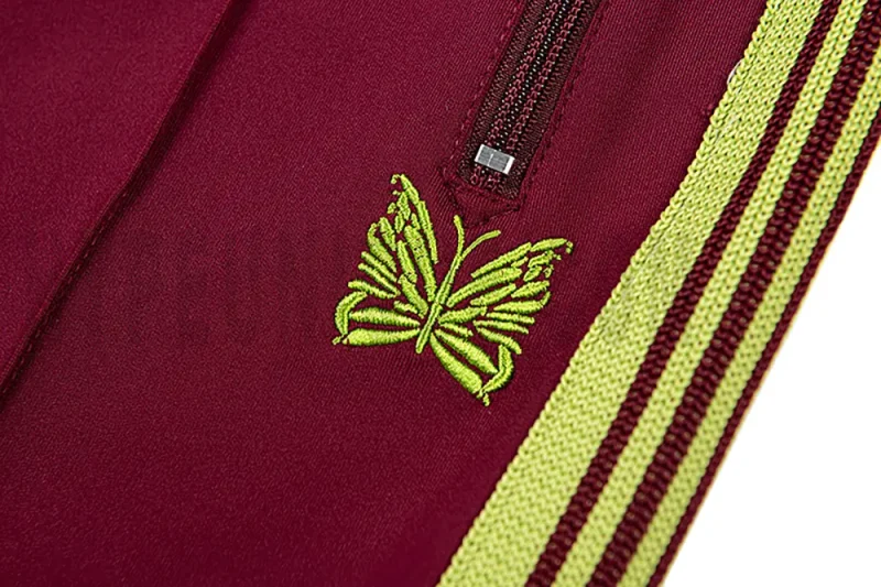 Close-up detail of the track pants pocket and delicate butterfly embroidery.